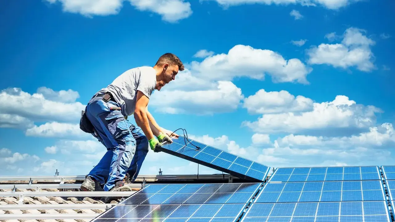 Mann installiert Solarmodule auf einem Dach. Die Sonne als Energiequelle wird genutzt, um saubere Energie zu erzeugen.
