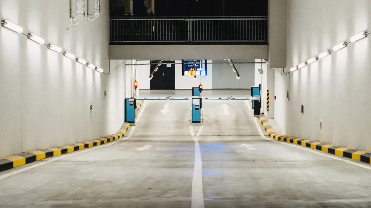 Einfahrt in eine Tiefgarage mit Schranken und Pfeilen, die den Weg weisen. Effizientes Parkraummanagement sorgt für Ordnung.