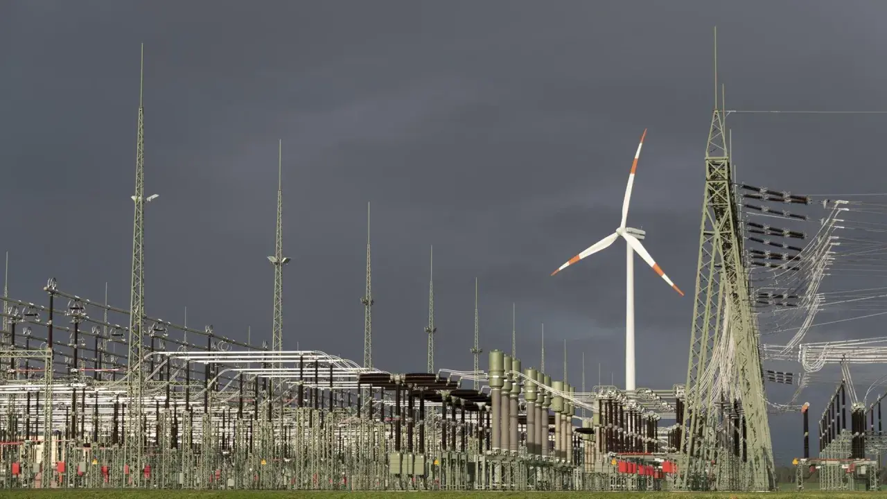 Ein Windrad und eine weitläufige Schaltanlage symbolisieren den Ausbau des Stromnetzes für erneuerbare Energien.