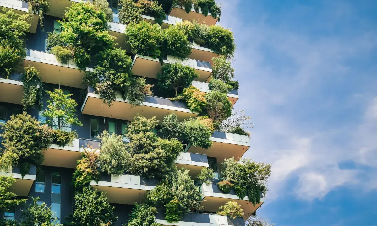 Ein Hochhaus, das wie ein vertikaler Garten aussieht. Bäume und Pflanzen wachsen auf den Balkonen und Fassaden. Ein Beispiel für klimagerechtes Bauen.
