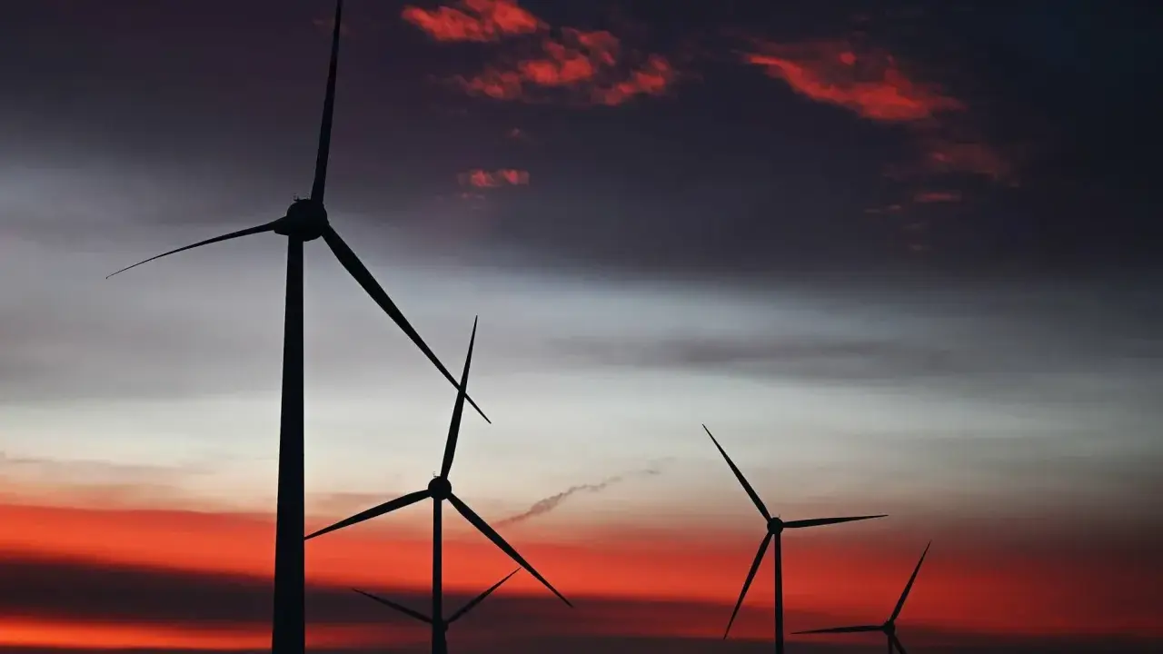 Silhouetten von Windkraftanlagen in den Niederlanden vor einem dramatischen Sonnenuntergang mit roten Wolken.