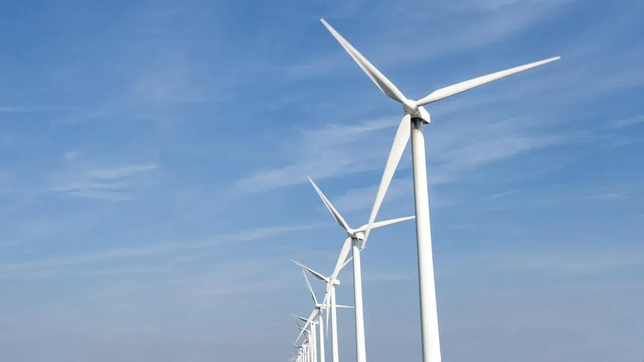 Reihe von Windrädern unter blauem Himmel, ein Symbol für Frankreichs Engagement für erneuerbare Energien.