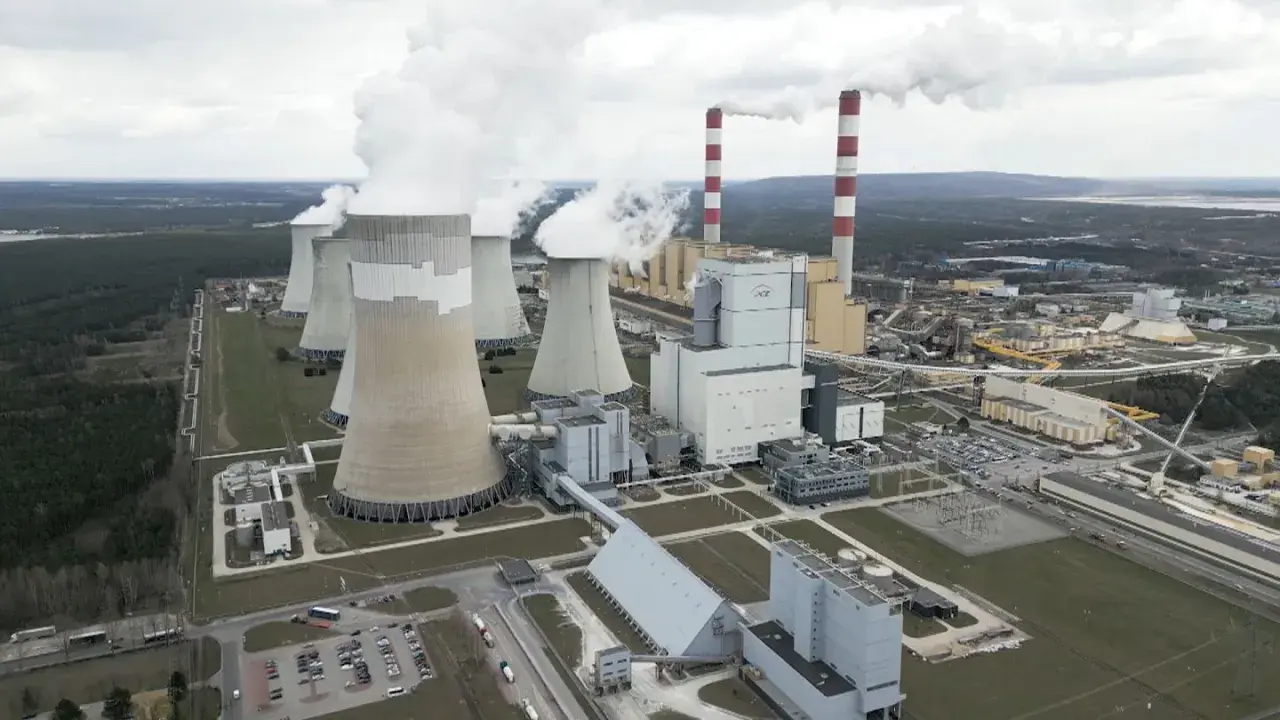 Große Kühltürme und Schornsteine einer polnischen Kraftwerksanlage, die Dampf abgeben. Der Strommix Polens wird hier sichtbar.