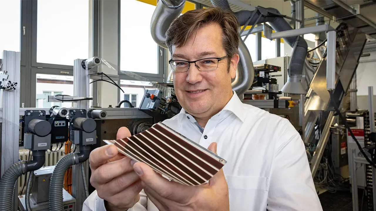Mann in Labor hält organische PV-Zelle. Die flexible Solarzelle mit Streifen ist ein Produkt fortschrittlicher Forschung.