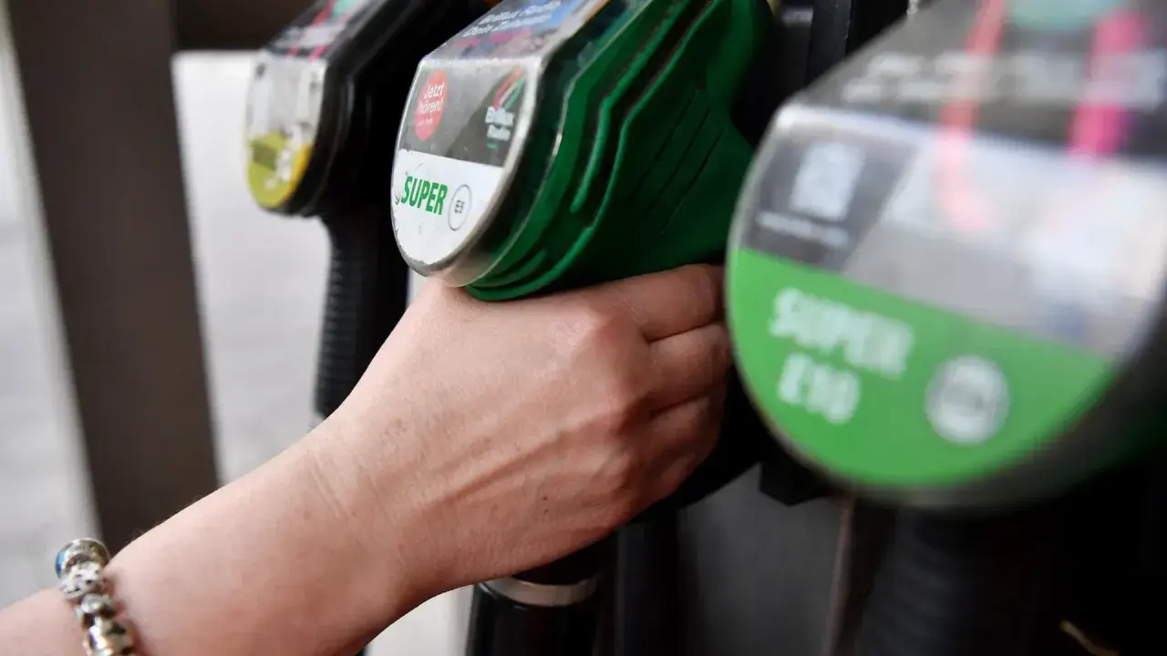 Hand greift nach Zapfhahn. Der steigende CO2-Preis macht sich beim Tanken bemerkbar.