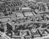 Luftaufnahme einer Siedlung mit vielen Hochhäusern und Wohnblöcken, die die Idee der autogerechten Stadt widerspiegelt.