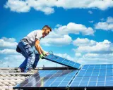Mann installiert Solarmodule auf einem Dach. Die Sonne als Energiequelle wird genutzt, um saubere Energie zu erzeugen.
