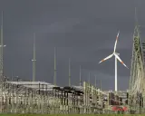 Ein Windrad und eine weitläufige Schaltanlage symbolisieren den Ausbau des Stromnetzes für erneuerbare Energien.