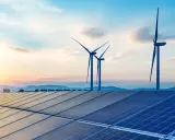 Solarpanels und Windräder im Sonnenuntergang symbolisieren die Versorgungssicherheit durch erneuerbare Energien.