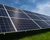 Reihen von Solarmodulen auf einer grünen Wiese unter blauem Himmel. Erneuerbare Energie durch Solarenergie.