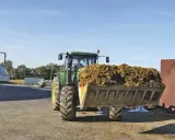 Traktor mit vollem Ladebehälter, bereit für die Biogasanlage. Mais und Gülle werden verarbeitet.