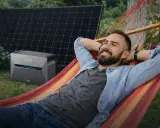 Mann entspannt in Hängematte, daneben Balkonkraftwerk Niedersachsen mit Solarmodulen.