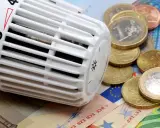 Thermostat mit Euro-Münzen und Scheinen. Heizkosten steigen, CO2-Geld wird knapp.