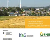Windräder über einem Dorf und goldenen Feldern. Die Frage, welche erneuerbare Energie die beste ist, wird hier visuell angedeutet.