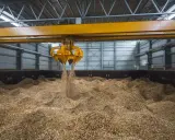 Ein Greifer lädt Holzspäne, ein Beispiel für Biomasse, in einen Lagerraum.