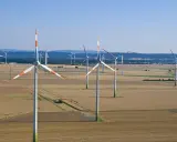 Großer onshore windpark in einer weiten Feldlandschaft unter blauem Himmel.