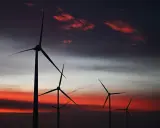 Silhouetten von Windkraftanlagen in den Niederlanden vor einem dramatischen Sonnenuntergang mit roten Wolken.