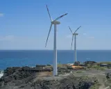 Zwei Windräder stehen an einer felsigen Küste Spaniens. Sie sind Teil des Strommixes und erzeugen saubere Energie.