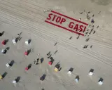 Menschen bilden auf einem Strand "STOP GAS!" als Zeichen für Deutschland klimaneutral. Viele Strandkörbe sind zu sehen.