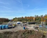 Baustelle mit großen Wasserbehältern und blauen Containern. Hier wird gezeigt, wie funktioniert geothermie mit Erdwärme.