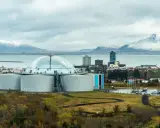 Große Kuppel und Tanks, Teil der island stromerzeugung, mit schneebedeckten Bergen im Hintergrund.