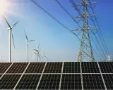 Solarpanels und Windräder, Teil von regenerativen Kraftwerken, unter blauem Himmel mit Strommasten.
