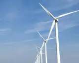 Reihe von Windrädern unter blauem Himmel, ein Symbol für Frankreichs Engagement für erneuerbare Energien.
