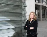Frau Kemfert steht selbstbewusst vor einer modernen Glasfassade.