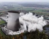 Ein Kühlturm stürzt ein, Staubwolken steigen auf. Ein Symbol für den **Atomausstieg Deutschland**.