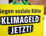 Gelbe Tafel mit schwarzer Schrift: "Gegen soziale Kälte KLIMAGELD JETZT!". Eine Forderung nach sozialer Gerechtigkeit im Klimaschutz.