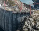 Bau einer gewaltigen Staumauer, die an Pumpspeicherkraftwerke in Deutschland erinnert. Kräne ragen in den Himmel, während die Betonkonstruktion wächst.