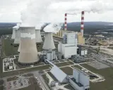 Große Kühltürme und Schornsteine einer polnischen Kraftwerksanlage, die Dampf abgeben. Der Strommix Polens wird hier sichtbar.