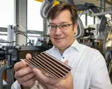 Mann in Labor hält organische PV-Zelle. Die flexible Solarzelle mit Streifen ist ein Produkt fortschrittlicher Forschung.