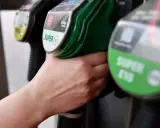 Hand greift nach Zapfhahn. Der steigende CO2-Preis macht sich beim Tanken bemerkbar.