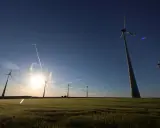 Windräder im Feld bei Sonnenuntergang, ein Symbol für den Windkraftausbau Deutschland. Kondensstreifen kreuzen den blauen Himmel.