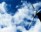 Eine Kleinwindkraftanlage in NRW dreht sich im blauen Himmel mit Wolken.