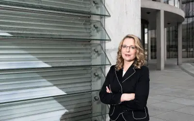 Frau Kemfert steht selbstbewusst vor einer modernen Glasfassade.