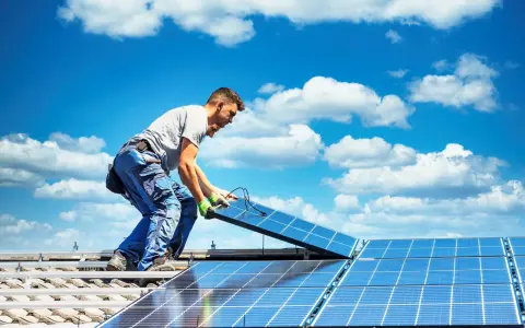 Mann installiert Solarmodule auf einem Dach. Die Sonne als Energiequelle wird genutzt, um saubere Energie zu erzeugen.