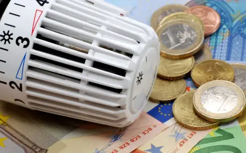 Thermostat mit Euro-Münzen und Scheinen. Heizkosten steigen, CO2-Geld wird knapp.