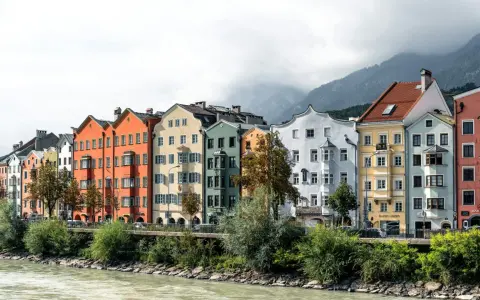 Bunte Häuserzeile am Flussufer, ein Beispiel dafür, was ein Ballungsraum ist: dicht bebaut, mit Bergen im Hintergrund.
