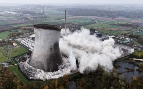 Ein Kühlturm stürzt ein, Staubwolken steigen auf. Ein Symbol für den **Atomausstieg Deutschland**.