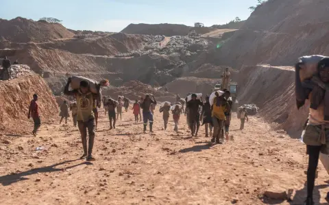 Kinder tragen schwere Säcke im Lithium-Abbau. Die harte Arbeit im Steinbruch zeigt die Realität von Kinderarbeit.