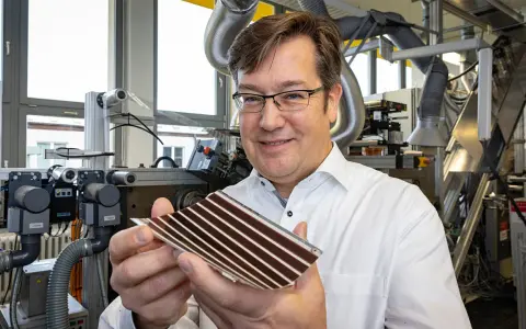 Mann in Labor hält organische PV-Zelle. Die flexible Solarzelle mit Streifen ist ein Produkt fortschrittlicher Forschung.