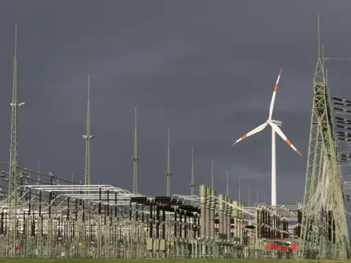 Ein Windrad und eine weitläufige Schaltanlage symbolisieren den Ausbau des Stromnetzes für erneuerbare Energien.