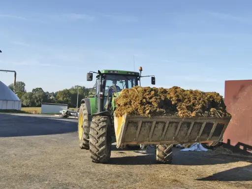Traktor mit vollem Ladebehälter, bereit für die Biogasanlage. Mais und Gülle werden verarbeitet.