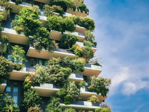 Ein Hochhaus, das wie ein vertikaler Garten aussieht. Bäume und Pflanzen wachsen auf den Balkonen und Fassaden. Ein Beispiel für klimagerechtes Bauen.