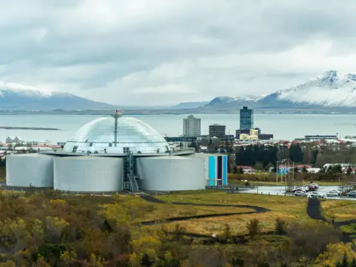 Große Kuppel und Tanks, Teil der island stromerzeugung, mit schneebedeckten Bergen im Hintergrund.