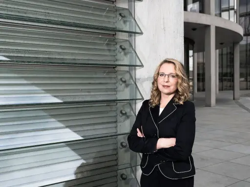 Frau Kemfert steht selbstbewusst vor einer modernen Glasfassade.