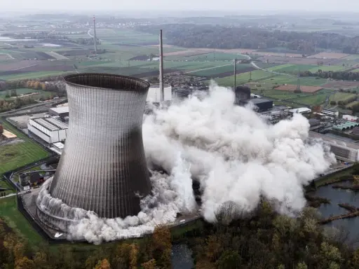 Ein Kühlturm stürzt ein, Staubwolken steigen auf. Ein Symbol für den **Atomausstieg Deutschland**.
