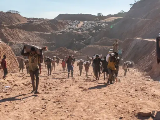 Kinder tragen schwere Säcke im Lithium-Abbau. Die harte Arbeit im Steinbruch zeigt die Realität von Kinderarbeit.